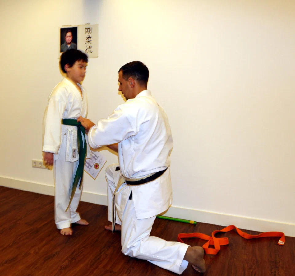 Sensei Aleksey Konovalov bindet Leon Rubinov nach bestandener Prüfung den grünen Gurt um